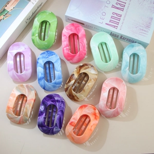 Flat lay of eleven marble textured hair claws in various colors on beige background