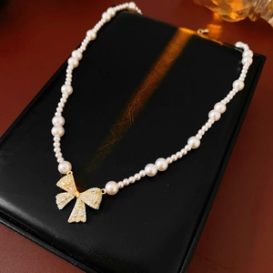 Detailed view of pearl bow pendant with zircons on a luxury black leather base