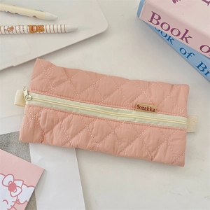 Detail of pink quilted pencil case showing soft rhombus texture and woven brand label