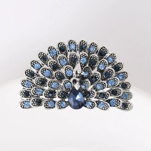 Macro detail of silver peacock brooch featuring sparkling blue crystals and teardrop gemstone