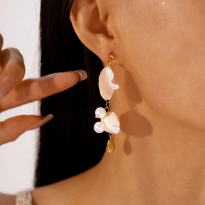 Detailed view of long baroque pearl earrings with golden shell charms for women