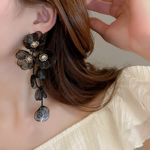 Close-up of long black flower tassel earrings with zircons worn by a model
