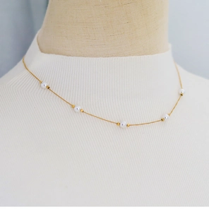 Close-up of elegant gold chain with five white round pearls on a stylish mannequin