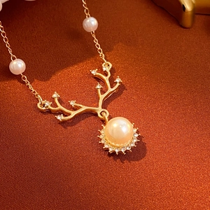 Golden elk antler pearl necklace with diamond accents on textured fabric background