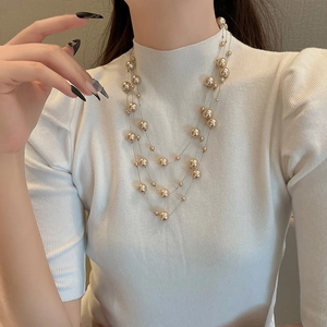 Détail du collier de perles multicouches en métal doré et perles de champagne