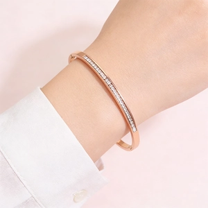 Detail of rose gold stainless steel bangle with pavé crystals on a female wrist