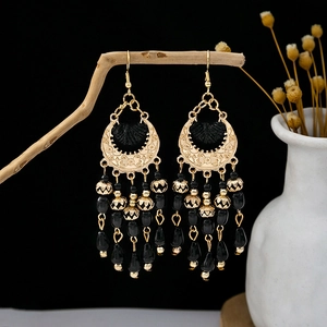 Bohemian crescent drop earrings with black beaded tassels on a rustic branch display