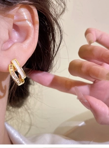 Detail of double-layer gold rectangle earrings with white shell inlay worn by model