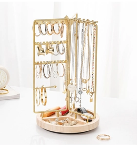 Detailed view of golden metal jewelry stand with rotating hooks and natural wooden tray base