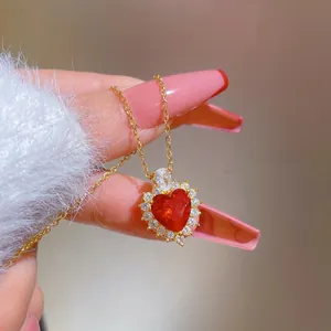 Macro shot of a gold heart necklace with a large red crystal and white zircon pavé