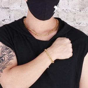 Dettaglio della collana e del bracciale Figaro dorati su un modello maschile stile street