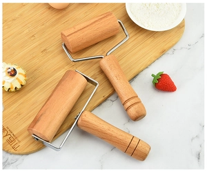 Close-up of dual-head beech wood rolling pins with stainless steel brackets on a board