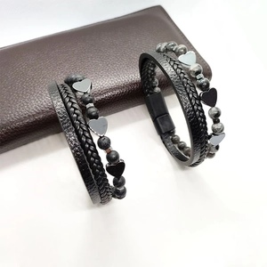 Dettagli dei bracciali di coppia in pelle intrecciata con ciondoli a cuore e chiusura magnetica