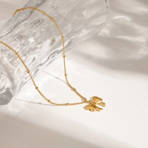 Elegant gold bow necklace with fine bead chain and butterfly pendant on white background