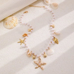Detail of bohemian starfish and shell necklace on a sandy beach background