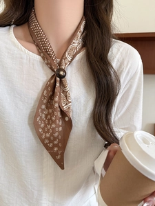 Detail of dark brown paisley silk scarf necklace with a round buckle and coffee scene