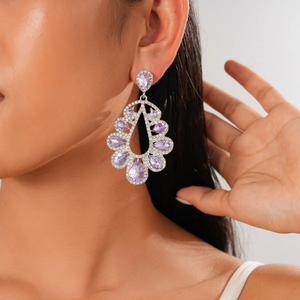 Close-up of silver teardrop earrings with purple crystal and pave diamonds on model