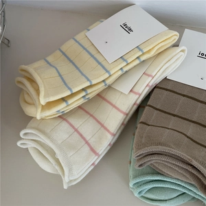 Folded Morandi-colored ribbed crew socks with stripes and minimalist paper labels