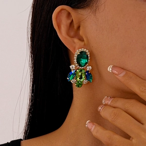 Close-up of vintage emerald and sapphire crystal drop earrings on a female model