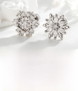 Detailed view of silver snowflake earrings with zirconia and pearls on titanium steel posts