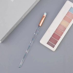 Angled eyebrow brush with crystal glitter handle and rose gold ferrule on makeup desk