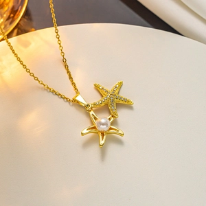 Macro detail of gold necklace with twin starfish pendants featuring zircon and pearl