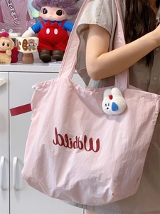 Pink drawstring canvas tote bag with red ribbon detail and a white plush bunny charm