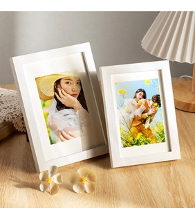 Detail of white wood grain photo frames with thick paper liners in a cozy home setting