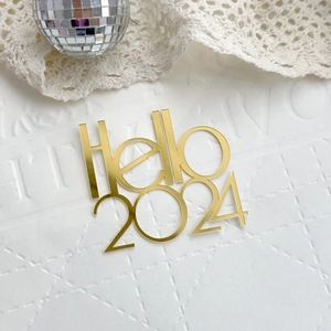 Close-up of gold mirror acrylic 'Hello 2024' cake topper for New Year celebration