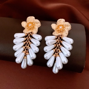 Detail of vintage gold flower earrings with elegant white pearl tassels and zircon