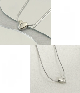 Dettaglio macro di ciondoli per collana in acciaio inossidabile a forma di cuore con lettere E e A