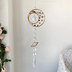 Detail of moon-shaped suncatcher with purple crystal stones and Saturn charm