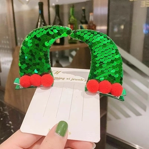 Detail of green sequin Christmas hat hair clips with red pompoms on white display card