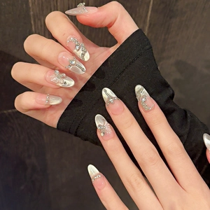Détail macro d'ongles amande avec effet œil de chat et breloques papillon argentées 3D