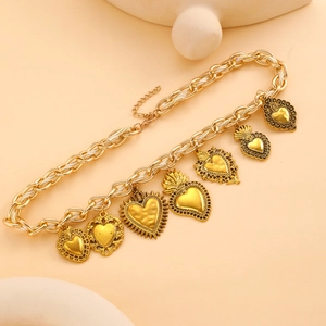 Detailansicht der goldenen Halskette mit mehreren Sacred-Heart-Anhängern im Vintage-Stil