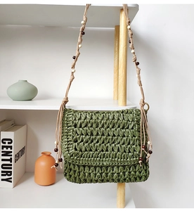 Close-up of moss green woven straw crossbody bag with wooden bead strap details