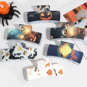 Set of 6 Halloween hair claws featuring pumpkin ghost and bat prints on a white surface