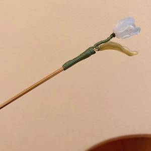 Detail of a handmade Chinese hairpin with green silk thread and blue tulip bud charm