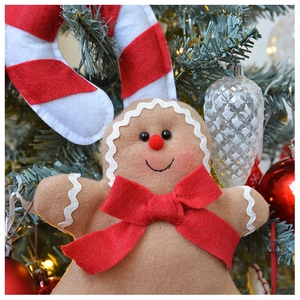 Detailed view of gingerbread man felt ornament with red bow hanging on a Christmas tree