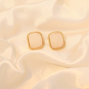 Detailed view of square cream resin stud earrings with gold-plated metal borders