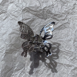 Close-up of liquid metal butterfly hair claw with rhinestones and hollow wing design