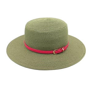 Detail of olive green woven straw hat featuring a vibrant red band and gold buckle