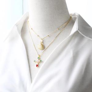 Gold layered necklace featuring a shell pendant and a pearl cross pendant with gems