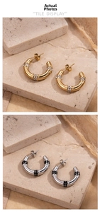 Macro detail of C-shaped stainless steel earrings with micro-inlaid black and white stones
