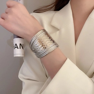 Détail d'un bracelet large argenté avec texture martelée et design en croix sur le poignet