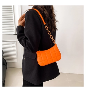 Gesteppte leuchtend orangefarbene Schultertasche mit Harzkettendetail am Modell