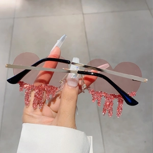 Detail of heart-shaped rimless sunglasses with pink crystal teardrop accents and gold temples