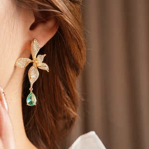 Detail of vintage flower earring with clear pavé petals and green pear-shaped gemstone