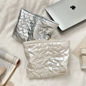 Close-up of heart-quilted PU makeup bags in metallic silver and pearlescent cream colors