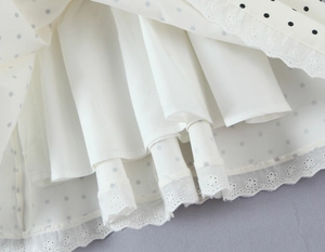 Detail of white polka dot dress featuring delicate lace hem and smooth inner lining